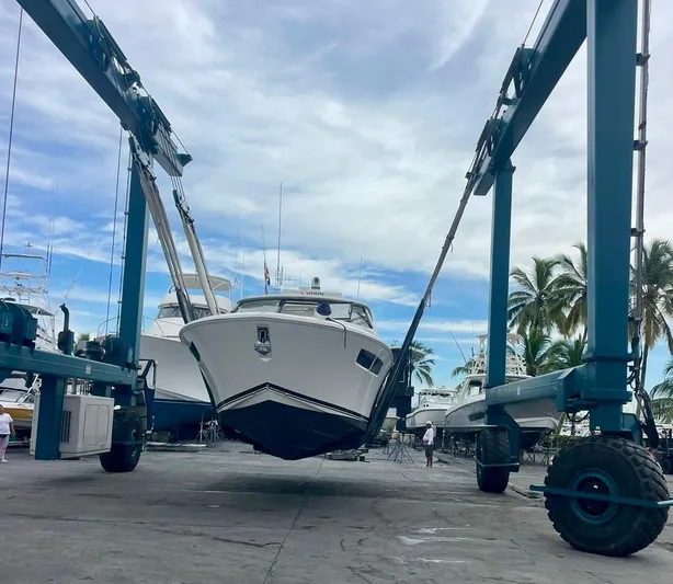  Yacht Photos Pics 2020 Pursuit DC 365 boat being lifted at a marina with palm trees and blue sky.