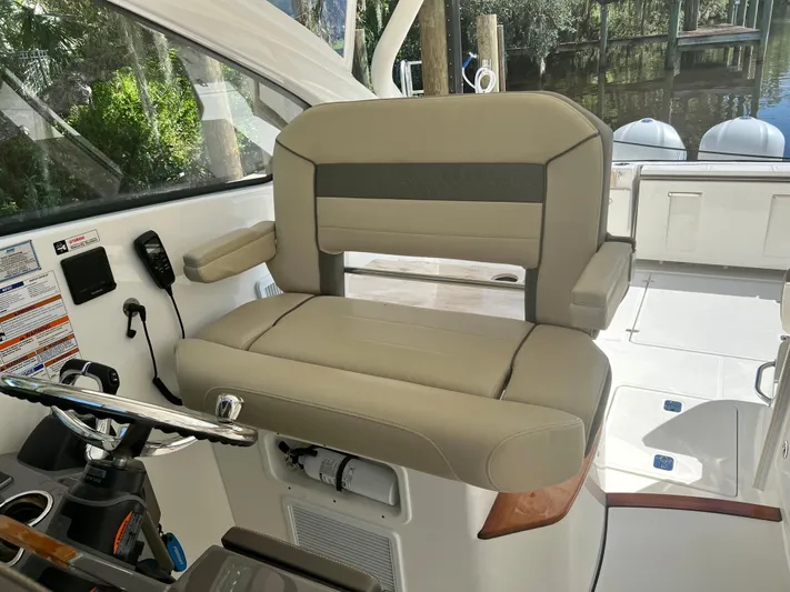  Yacht Photos Pics Captain's seat on 2020 Pursuit DC 365 boat, featuring beige upholstery and control panel.