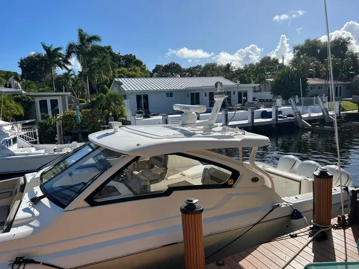  Yacht Photos Pics 2020 Pursuit DC 365 boat docked by waterfront homes under a clear blue sky.