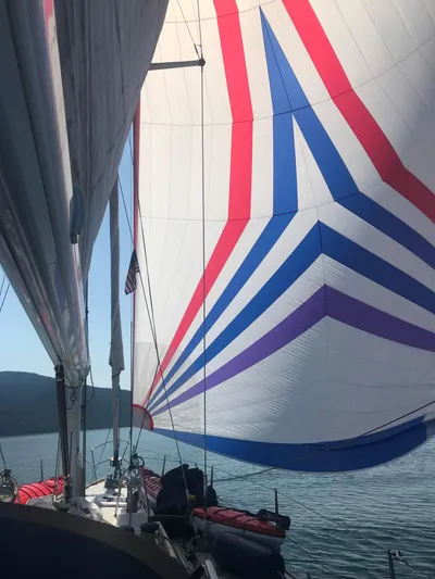 Imagine Yacht Photos Pics Sailing yacht J/44 with colorful spinnaker sail, 1990 model, on calm waters.