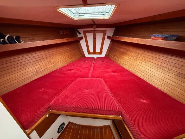 Imagine Yacht Photos Pics Interior of 1990 J Boats J/44 with red cushioned V-berth and wooden paneling.