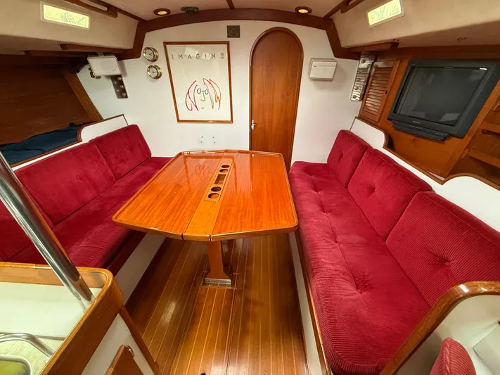 Imagine Yacht Photos Pics Interior of 1990 J Boats J/44 with red seating and wooden table.