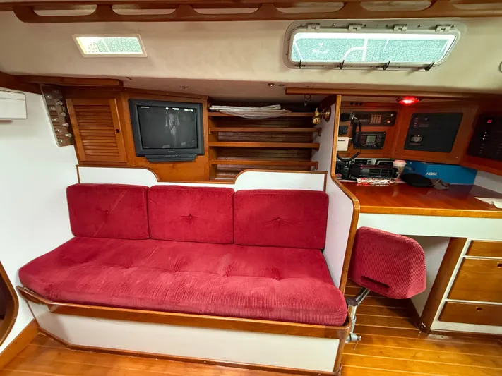Imagine Yacht Photos Pics Interior of 1990 J Boats J/44 sailboat with red cushioned seating and navigation equipment.