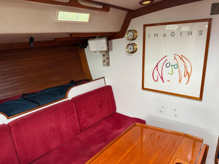 Imagine Yacht Photos Pics Interior of 1990 J Boats J/44 with red seating, wooden table, and wall art.