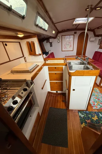 Imagine Yacht Photos Pics Interior of a 1990 J Boats J/44 sailboat featuring a compact kitchen with wood accents.