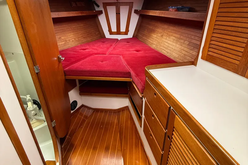 Imagine Yacht Photos Pics 1990 J Boats J/44 cabin interior with red bedding and wooden cabinetry.
