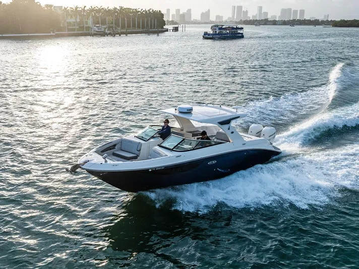  Yacht Photos Pics 2021 Sea Ray 350 SLX OB cruising on a scenic waterway with city skyline in the background.