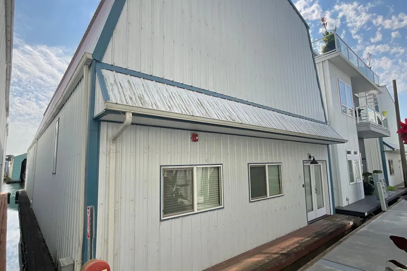  Yacht Photos Pics Custom 1995 boathouse with white siding and blue trim under a clear sky.