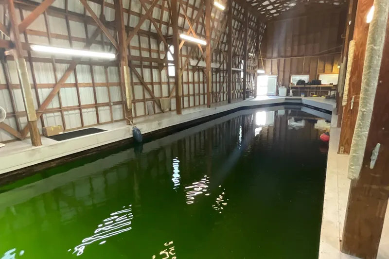  Yacht Photos Pics Interior of a 1995 custom boathouse with green water and wooden beams.