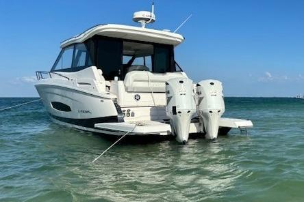2021 Regal 36 XO boat anchored in clear blue water, rear view.