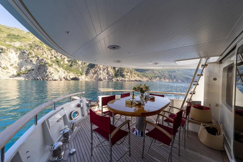  Yacht Photos Pics Luxurious 1986 Moonen 85 yacht deck with dining area, overlooking serene coastal waters.