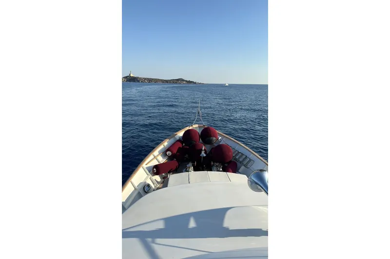  Yacht Photos Pics Bow view of 1986 Moonen 85 yacht cruising on calm sea near rocky coastline.