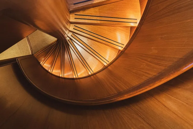  Yacht Photos Pics Spiral wooden staircase inside 1986 Moonen 85 yacht, showcasing elegant craftsmanship.