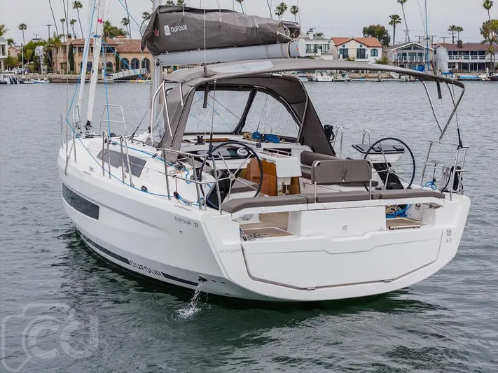 In Stock #042 Yacht Photos Pics 2023 Dufour 37 sailboat in marina, featuring dual steering wheels and spacious cockpit.