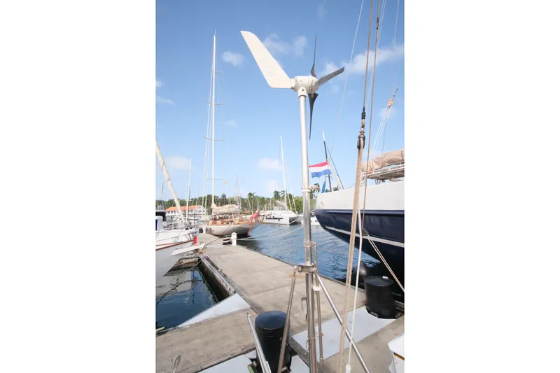 Blue Song Yacht Photos Pics 1984 Amel Maramu 45 sailboat docked with wind turbine, clear sky background.