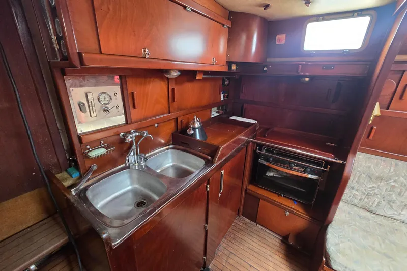 Blue Song Yacht Photos Pics 1984 Amel Maramu 45 yacht interior kitchen with wooden cabinetry and dual sinks.