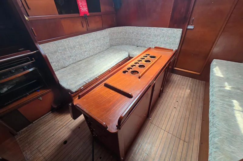 Blue Song Yacht Photos Pics Interior of 1984 Amel Maramu 45 sailboat with wooden table and cushioned seating.