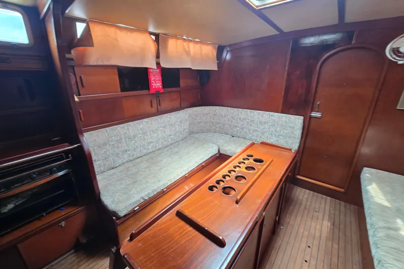 Blue Song Yacht Photos Pics Interior of 1984 Amel Maramu 45 sailboat with wooden furnishings and cushioned seating.