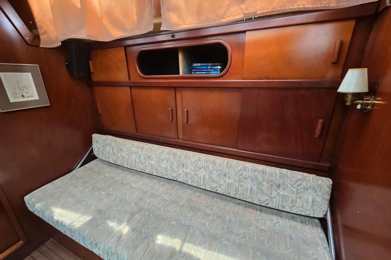 Blue Song Yacht Photos Pics Interior of 1984 Amel Maramu 45 sailboat with wooden cabinets and cushioned seating.