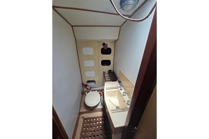 Blue Song Yacht Photos Pics 1984 Amel Maramu 45 yacht bathroom with sink, toilet, and wooden flooring.