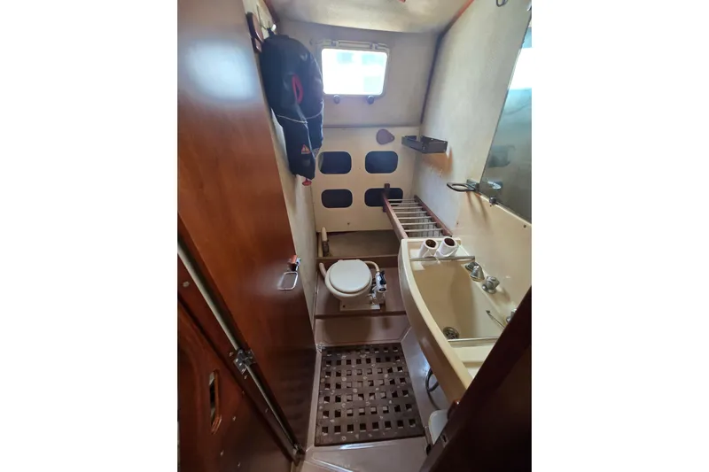 Blue Song Yacht Photos Pics 1984 Amel Maramu 45 yacht bathroom with sink, toilet, and wooden accents.