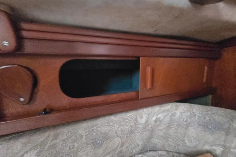 Blue Song Yacht Photos Pics Wooden interior storage on 1984 Amel Maramu 45 sailboat, featuring sliding doors and patterned upholstery.