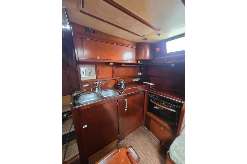 Blue Song Yacht Photos Pics 1984 Amel Maramu 45 yacht kitchen with wooden cabinetry and dual sinks.
