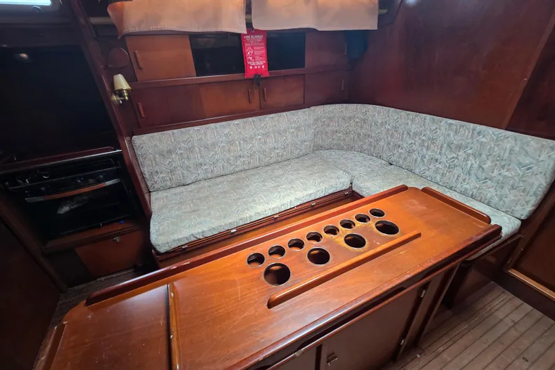 Blue Song Yacht Photos Pics Interior of 1984 Amel Maramu 45 sailboat with cushioned seating and wooden table.