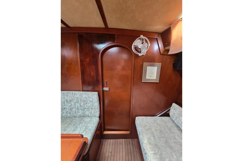 Blue Song Yacht Photos Pics Interior of 1984 Amel Maramu 45 sailboat with wood paneling and cushioned seating.