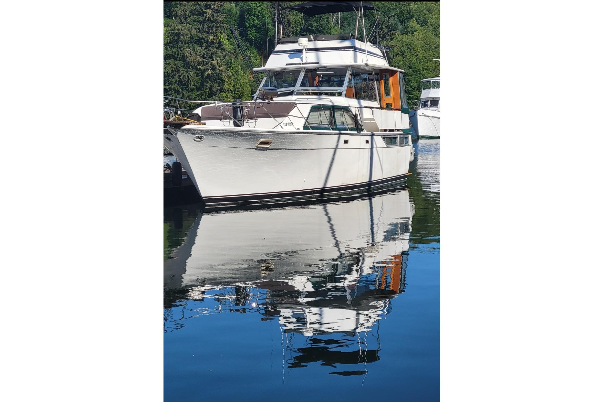 1977 Pacemaker 40 Motor Yacht reflecting on calm water, surrounded by lush greenery.
