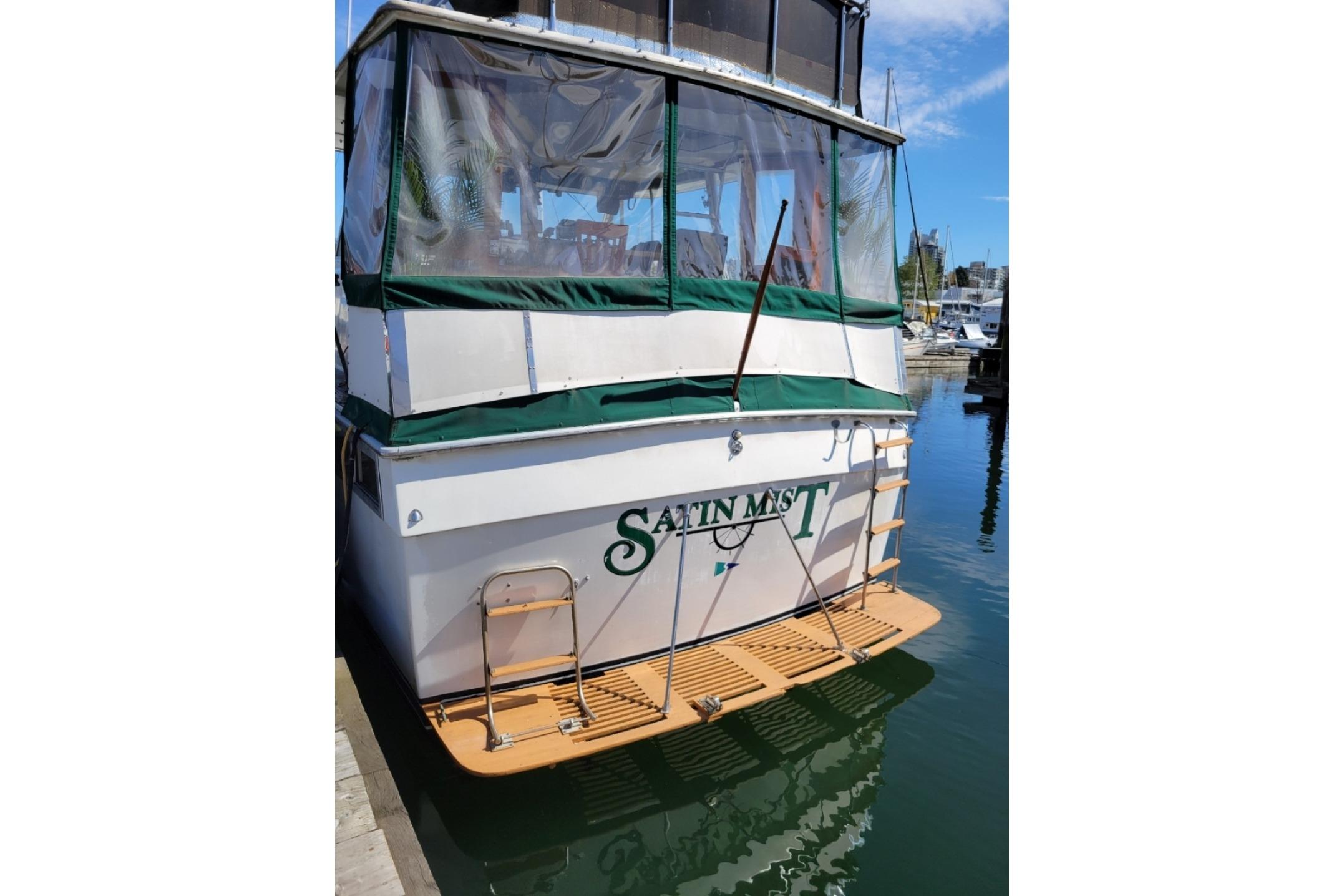 1977 Pacemaker 40 Motor Yacht docked, featuring a green canopy and wooden swim platform.