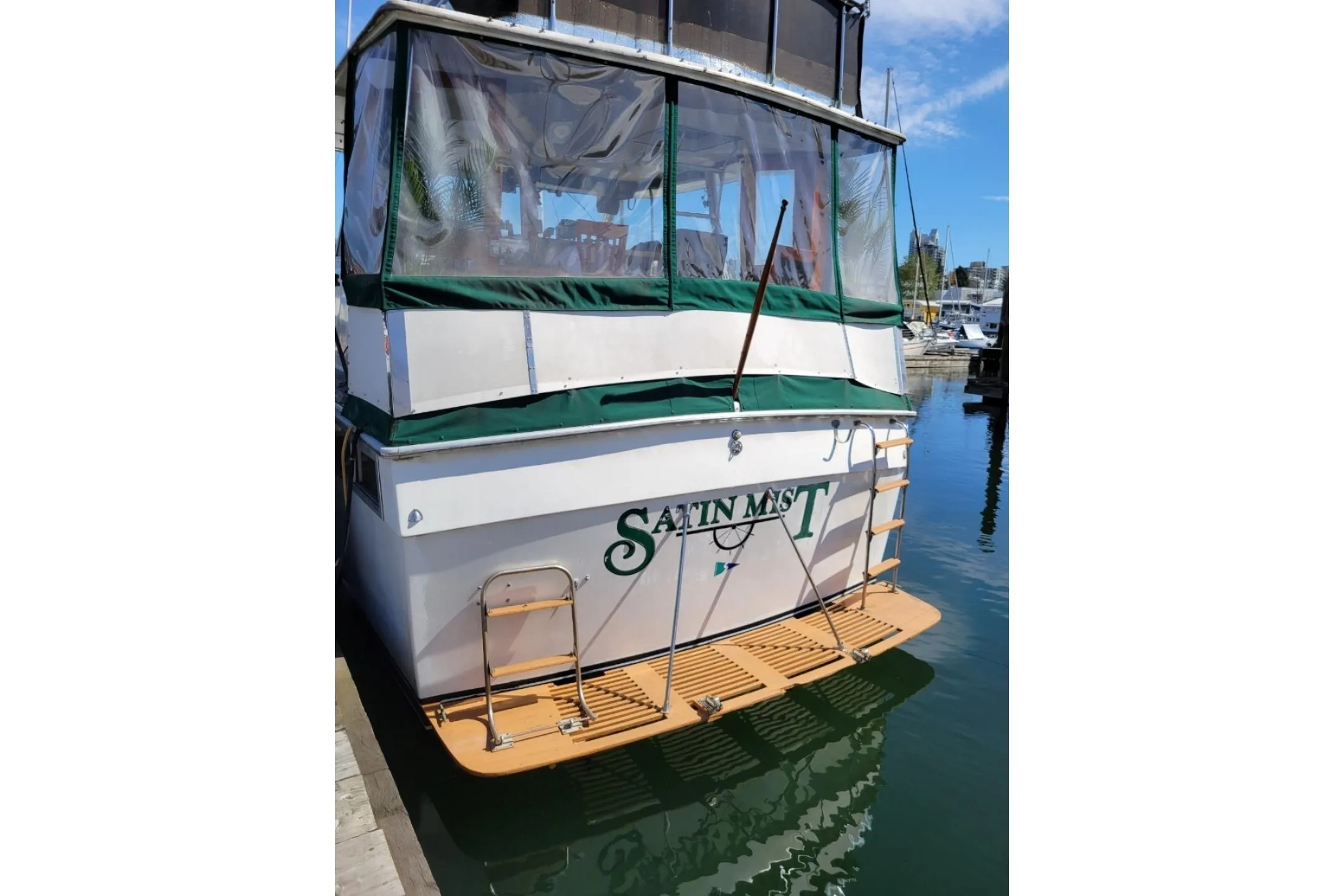 1977 Pacemaker 40 Motor Yacht docked, featuring a green canopy and wooden swim platform.