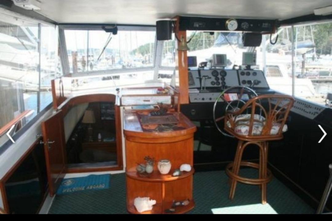 Interior of 1977 Pacemaker 40 Motor Yacht with helm, wooden accents, and marina view.