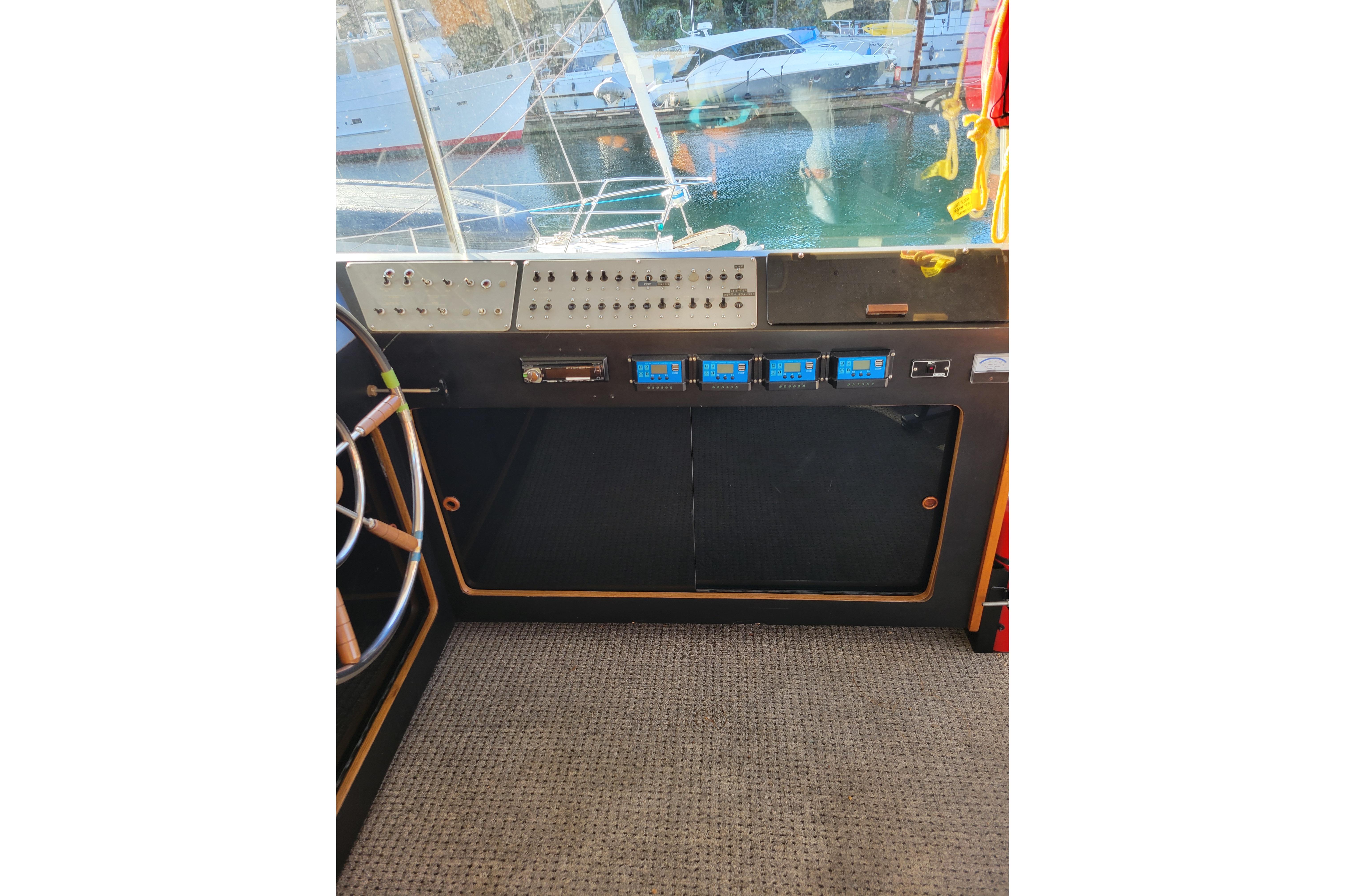 1977 Pacemaker 40 Motor Yacht helm with control panel and steering wheel, docked at marina.