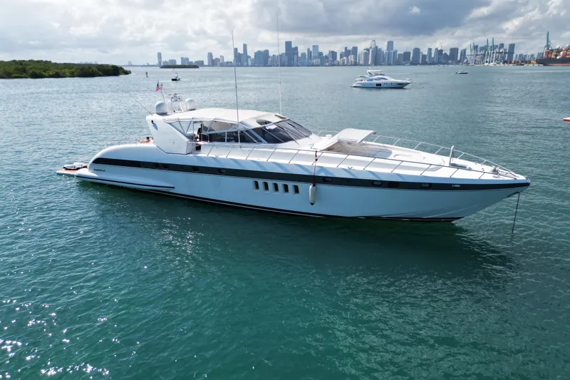  Yacht Photos Pics Luxurious 1999 Mangusta 80 yacht cruising near a city skyline on a sunny day.