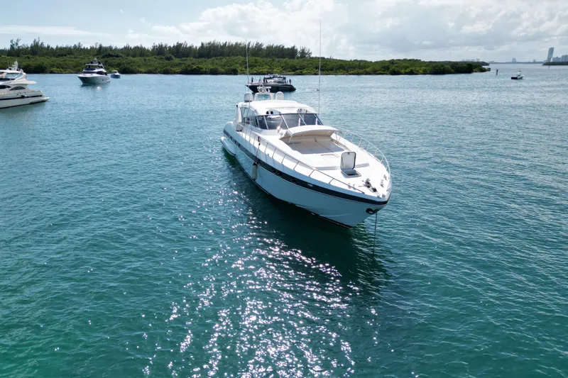  Yacht Photos Pics 1999 Mangusta 80 yacht anchored in clear blue water, surrounded by other boats.