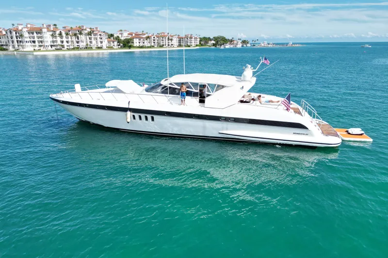  Yacht Photos Pics 1999 Mangusta 80 yacht cruising on turquoise waters near luxury waterfront residences.