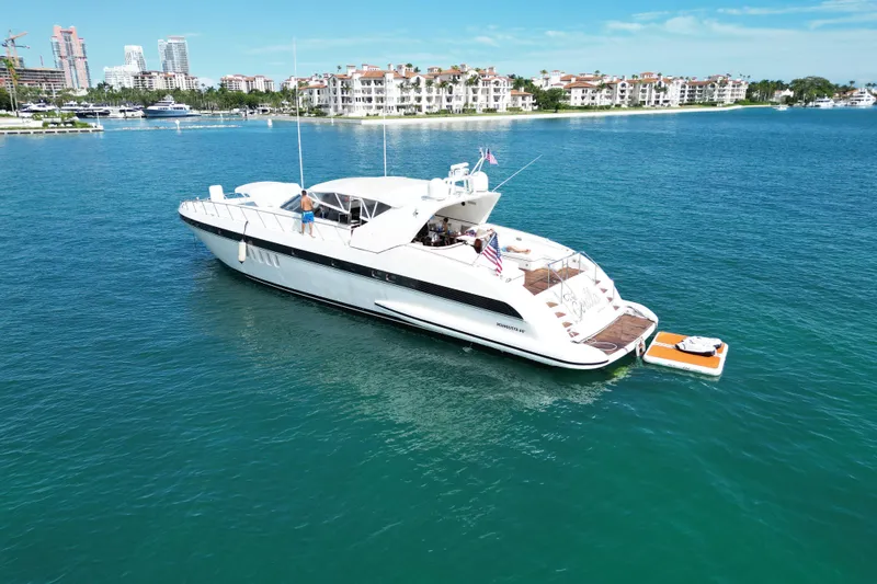  Yacht Photos Pics 1999 Mangusta 80 yacht cruising in clear blue waters near luxury waterfront residences.