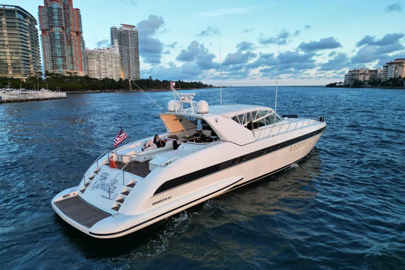  Yacht Photos Pics Luxurious 1999 Mangusta 80 yacht cruising near city skyline at sunset.