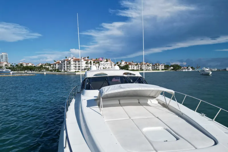  Yacht Photos Pics 1999 Mangusta 80 yacht cruising near luxury waterfront residences under a clear blue sky.