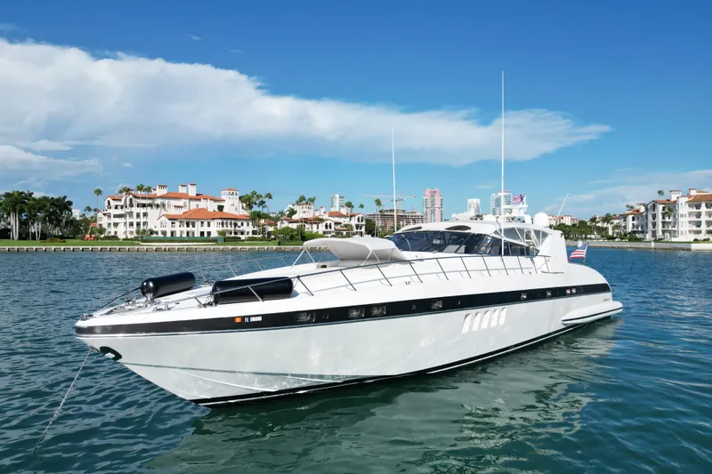 Yacht Photos Pics 1999 Mangusta 80 yacht cruising near luxury waterfront homes under a clear blue sky.