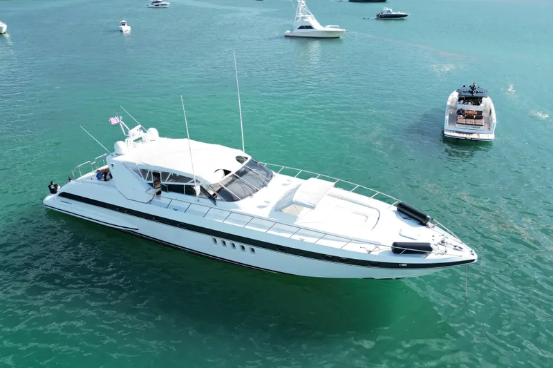  Yacht Photos Pics Luxurious 1999 Mangusta 80 yacht cruising in clear blue waters, surrounded by smaller boats.