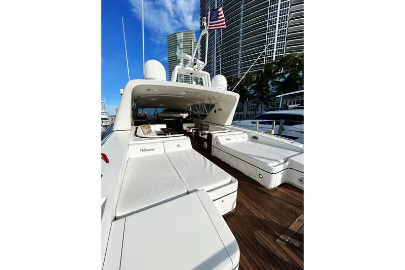  Yacht Photos Pics 1999 Mangusta 80 yacht with sleek design, docked near modern buildings, American flag visible.