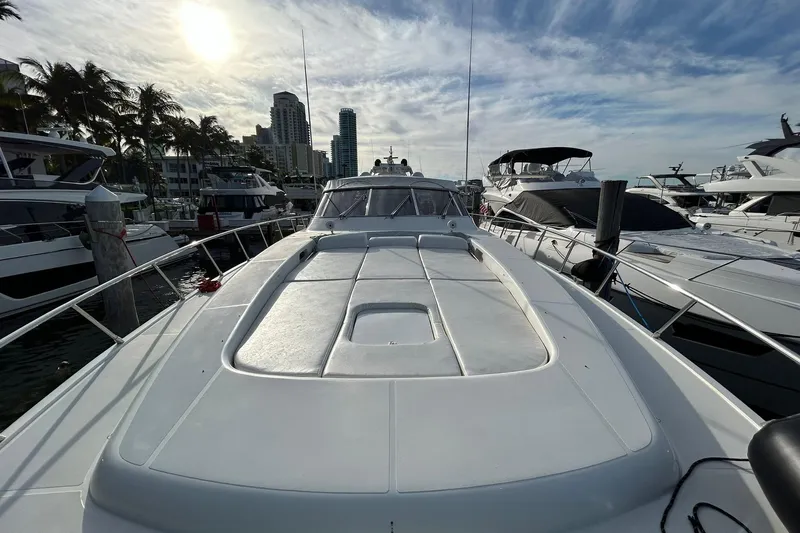  Yacht Photos Pics 1999 Mangusta 80 yacht docked at marina, with city skyline and palm trees in background.