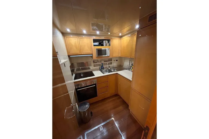  Yacht Photos Pics Compact kitchen in a 1999 Mangusta 80 yacht with wooden cabinets and modern appliances.