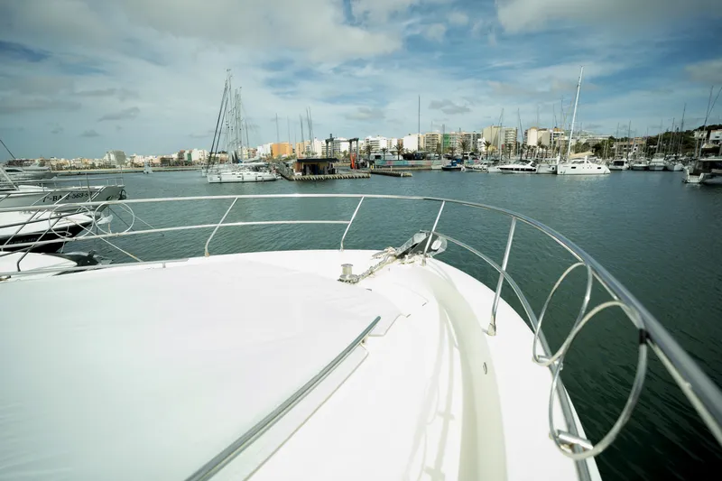  Yacht Photos Pics Bow view of 2014 Prestige 550 yacht in a marina with sailboats and cityscape.
