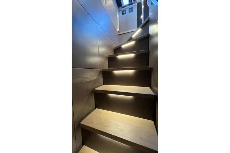  Yacht Photos Pics Illuminated wooden staircase inside 2024 Pershing 8X yacht, showcasing modern design.