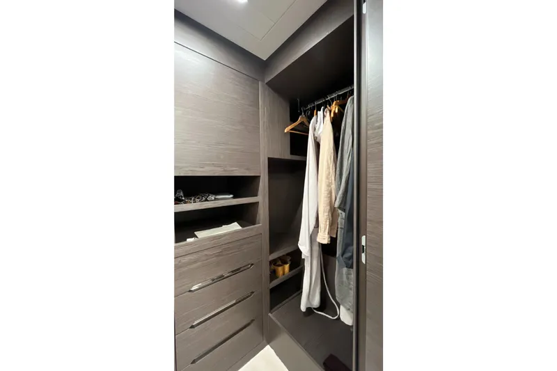  Yacht Photos Pics Luxurious wooden closet interior on the 2024 Pershing 8X yacht, featuring hanging clothes and shelves.