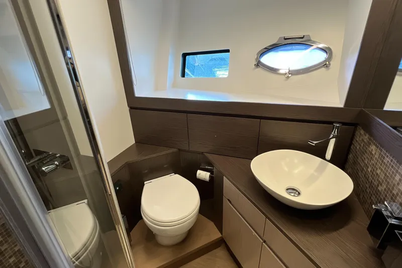  Yacht Photos Pics Luxurious bathroom interior of 2024 Pershing 8X yacht with modern fixtures and porthole window.