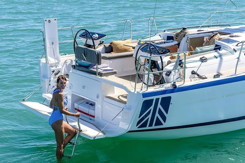  Yacht Photos Pics 2025 Dufour Yachts 37 sailboat with woman in blue swimsuit on ladder.